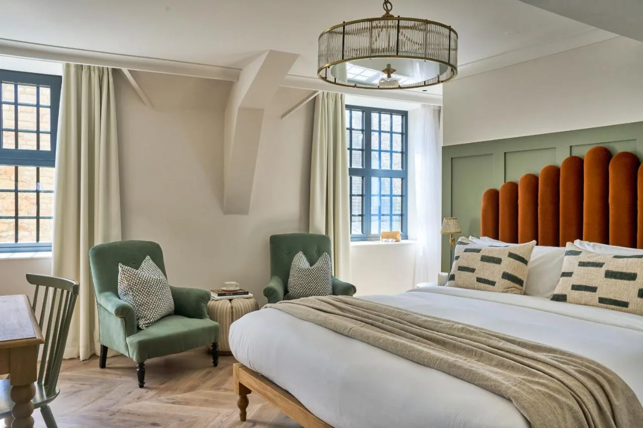 Bedroom with large bed and green armchairs at The Store, Broad Street, Oxford